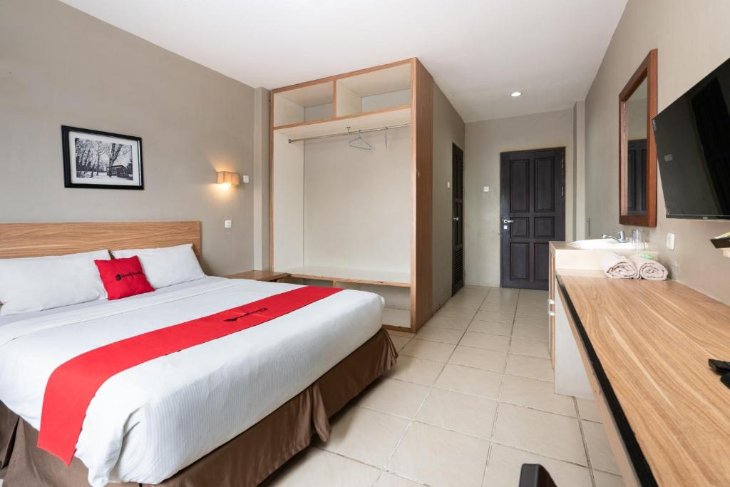 a bedroom with a large bed and a bathroom at RedDoorz Plus at Hotel Ulin Samarinda in Samarinda