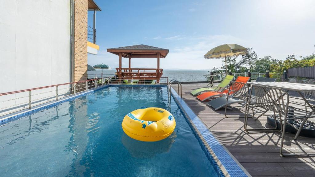 a swimming pool with a yellow ball in the water at Yeosu Eoneumeosjinnal Pension in Yeosu