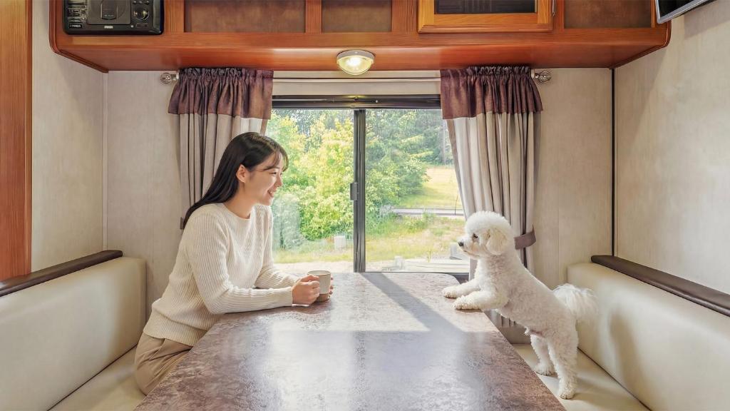 a woman sitting at a table with a stuffed teddy bear at Goseong Jjun Camping Pension in Goseong