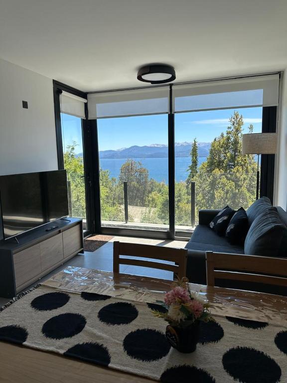 a living room with a couch and a large window at Amanecer del lago in San Carlos de Bariloche