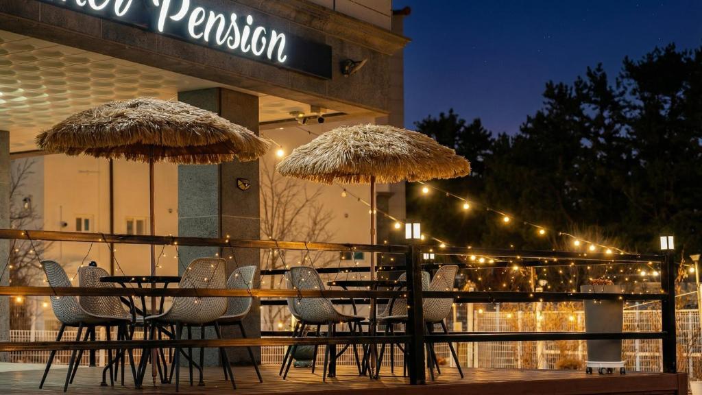 two tables and chairs with umbrellas in front of a building at Samcheok Lamer Pension in Samcheok