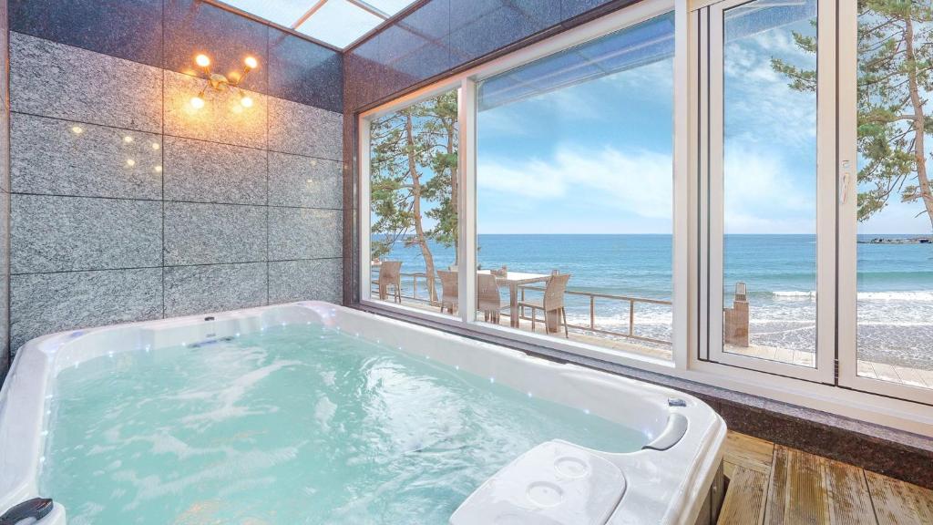 a bath tub in a room with a view of the ocean at Pohang Playbeach Poolvilla in Pohang