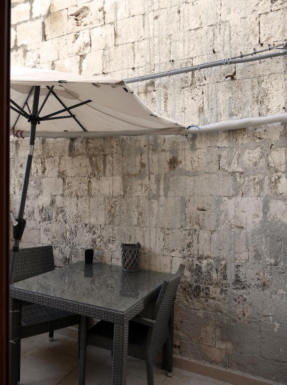 stół z parasolką obok ściany z cegły w obiekcie B&B Il Campanile w mieście Barletta