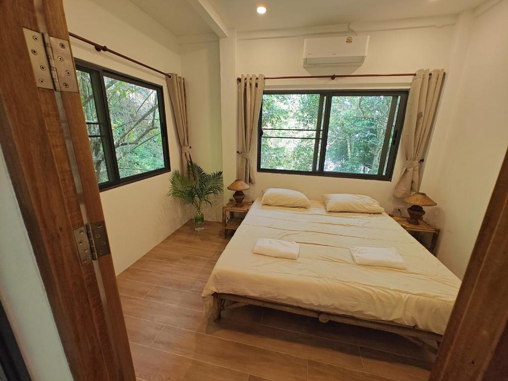 a bedroom with two beds and two windows at Ganesha Mouse House in Ko Phangan