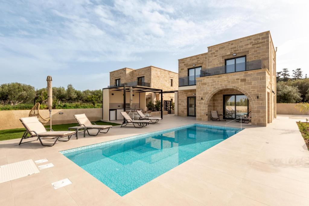 a villa with a swimming pool and a house at Golden Silence in Platanias
