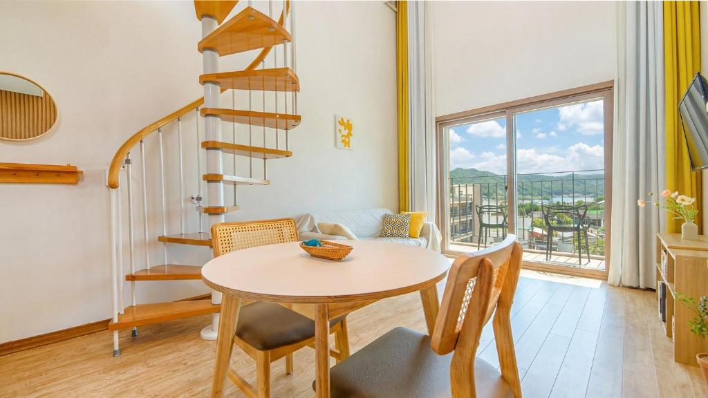a dining room with a table and a spiral staircase at Chuncheon Lio Pension in Chuncheon