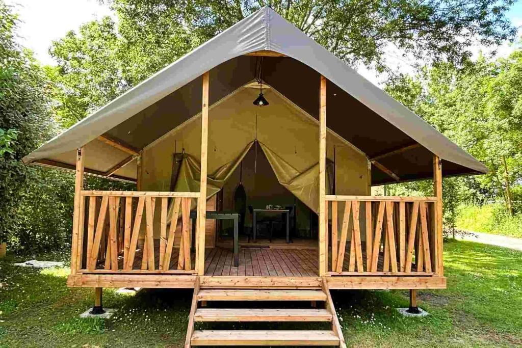 a tent with a wooden porch and a table inside at Lodge Mini-Wood in Les Rochettes