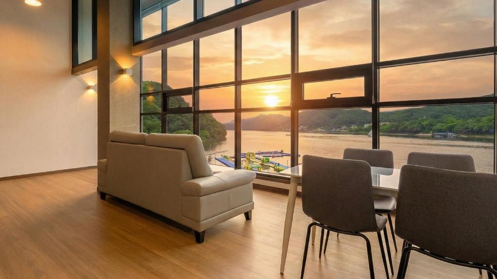 a living room with a table and chairs and a large window at Gapyeong Sungshine Pension in Gapyeong