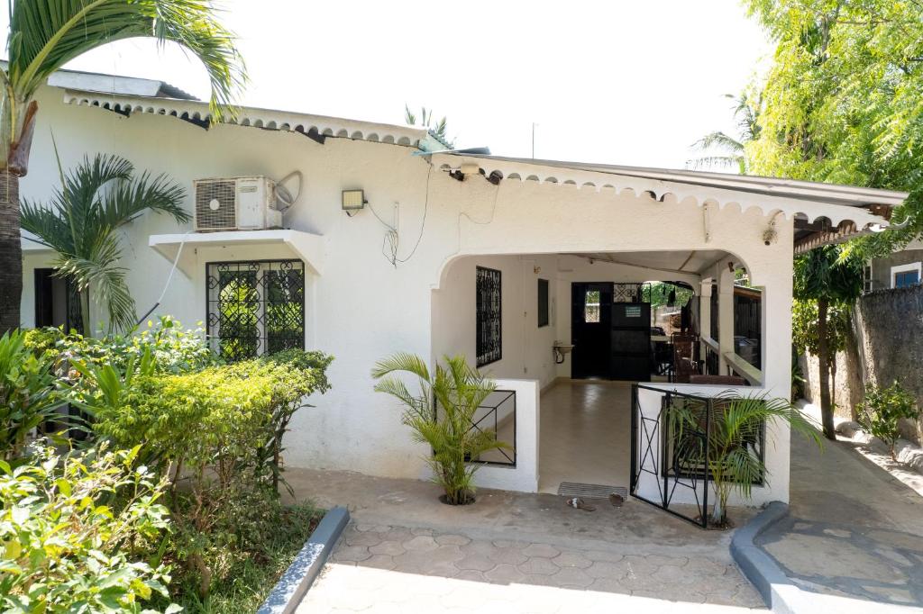 a white house with a gate and trees at Cosy Garner Haven Watamu in Watamu