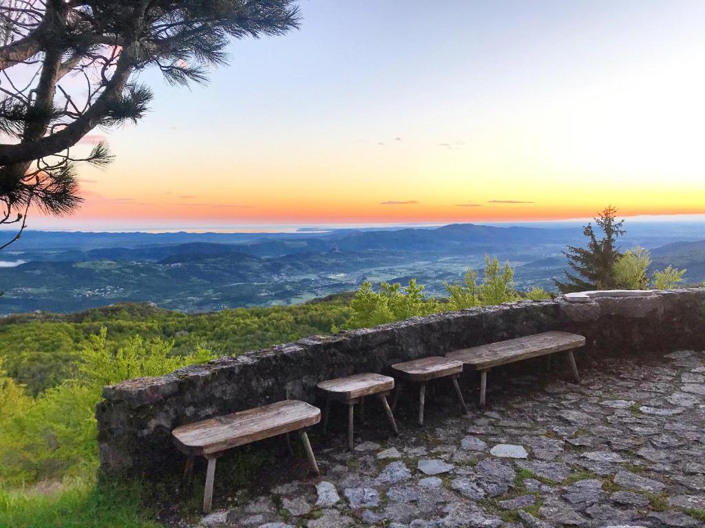 two benches sitting on top of a hill with a sunset at Penzion Sinji vrh in Zoll
