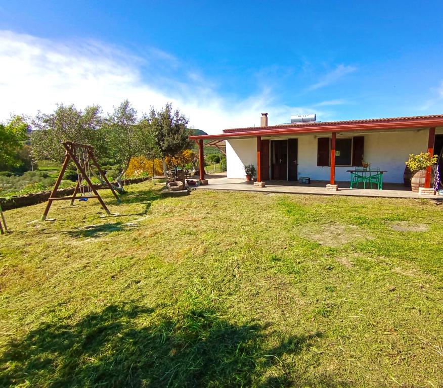 a house with a yard with a swing at Da Nonno Francesco in Teulada