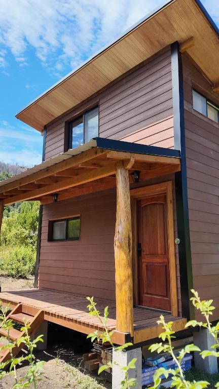 a house with a wooden porch and a large tree at Premium Cabin in El Bolsón in El Bolsón