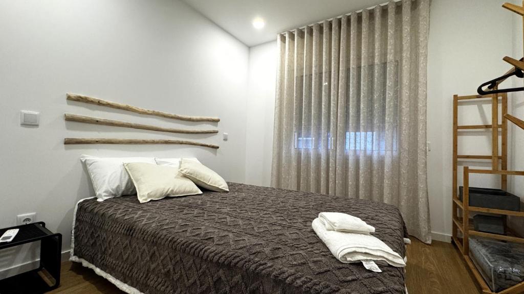 a bedroom with a bed with white pillows and a window at S'apartments New in Leiria