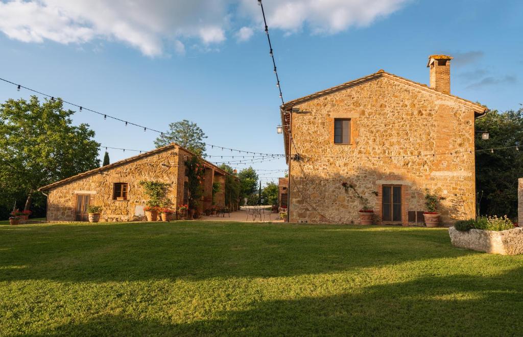 an old stone building with a grass yard at Podere Lamone a Monticchiello in Monticchiello