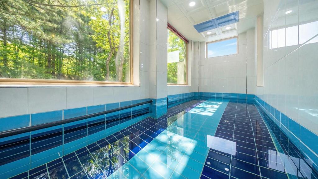 a swimming pool with a blue tile floor and windows at Gapyeong Namian Pool Villa in Gapyeong