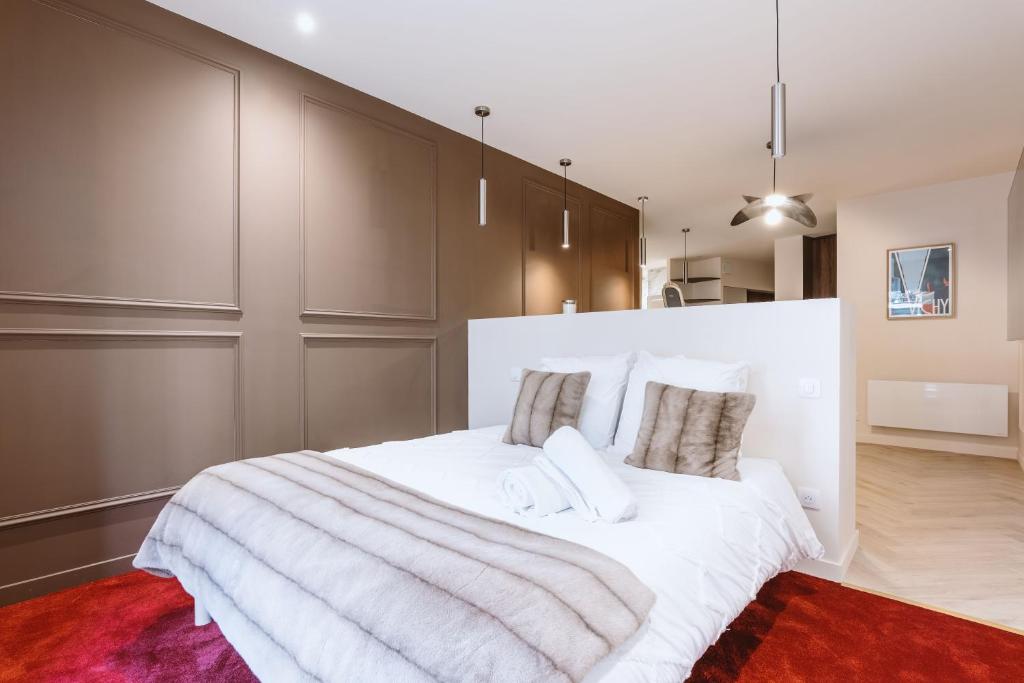 a bedroom with a large bed with white sheets and pillows at Suite Cognac - International Palace - Jacuzzi in Vichy