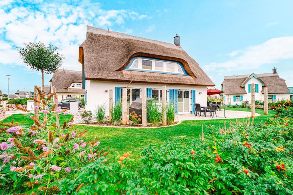 a house with a thatched roof with a garden at Kramerhof Ferienhaus Luv und Lee in Parow