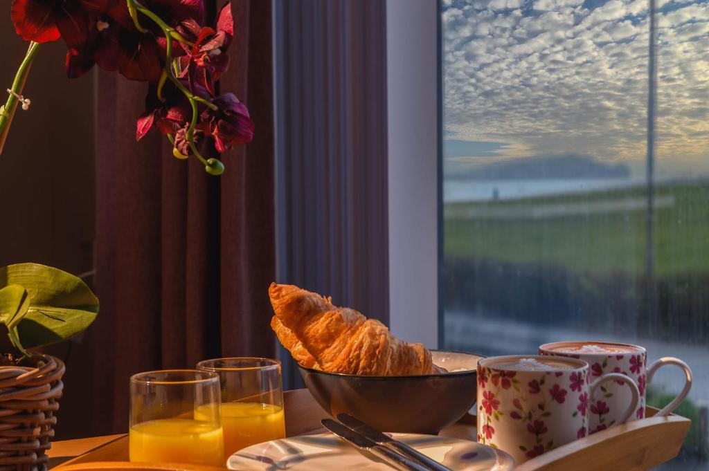 a table with a bowl of bread and a bowl of orange juice at Panoramic Sea-View Family Appartment , Free Parking, Sleeps 6 , Walk to Beach, Station, & Town in Newquay