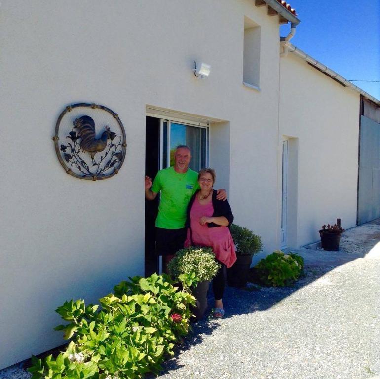 een man en een vrouw die buiten een huis staan bij Le Grillage a Poules in Gensac-la-Pallue