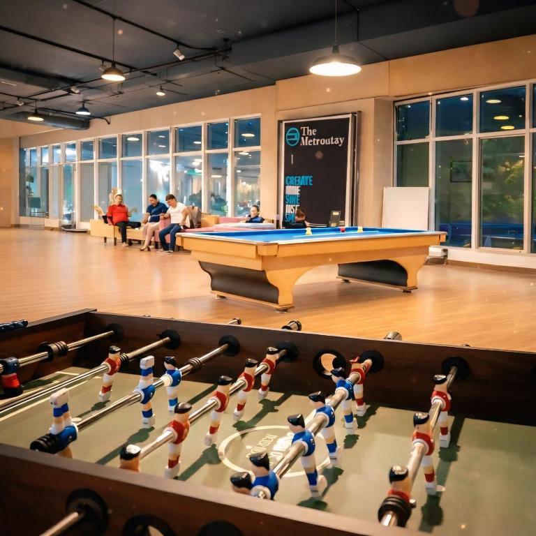 a pool table in a room with people sitting at Metro POD Hotel at New Delhi Metro & Railway Station in New Delhi