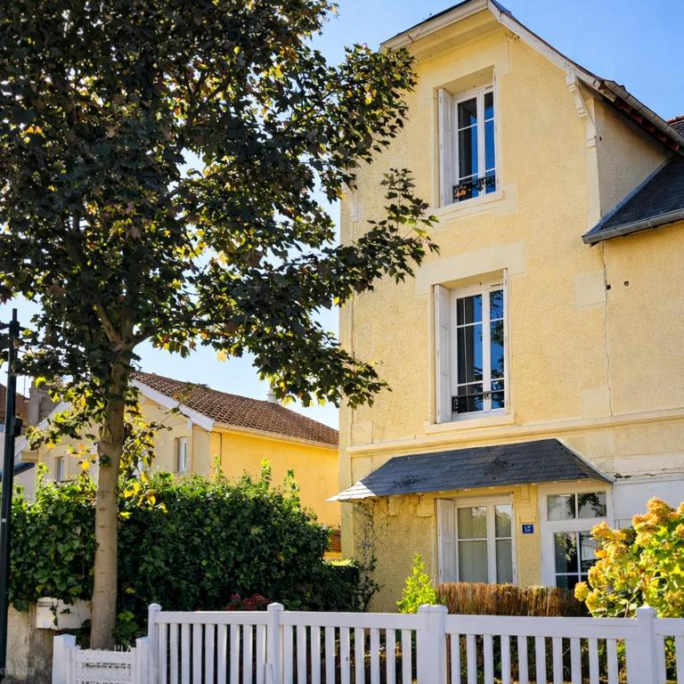 a white fence in front of a yellow house at Maison spacieuse au coeur du Centre - Plage à pied in Luc-sur-Mer