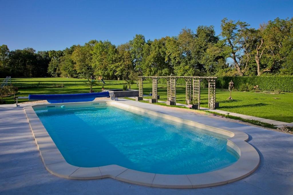 a large pool with blue water in a yard at La Bonne Vie Gite in Chaunay