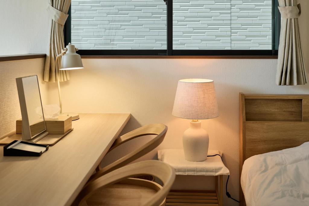 a bedroom with a desk with a lamp and a bed at 宿 花甜 in Osaka
