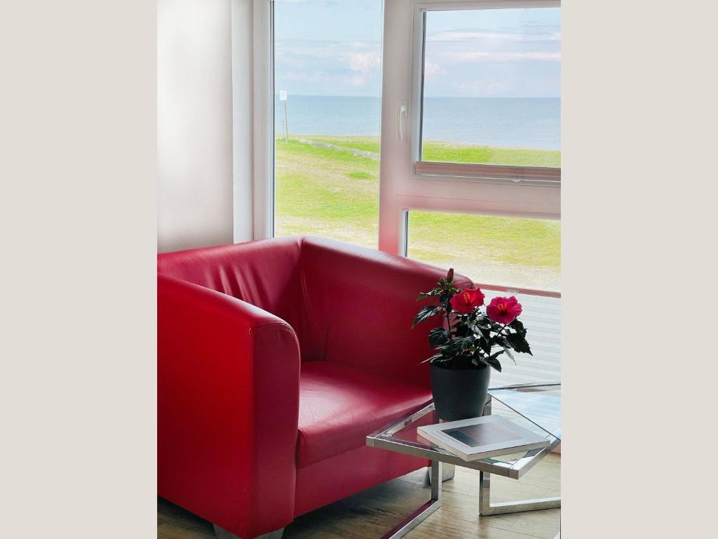 a red chair sitting in front of a window at Apartment Rickmer Rickmers Teichhof Fehmarn in Wenkendorf