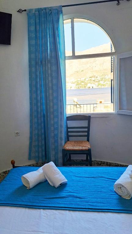 a bedroom with a bed with a window and a chair at Dimitreli Beach House in Telendos