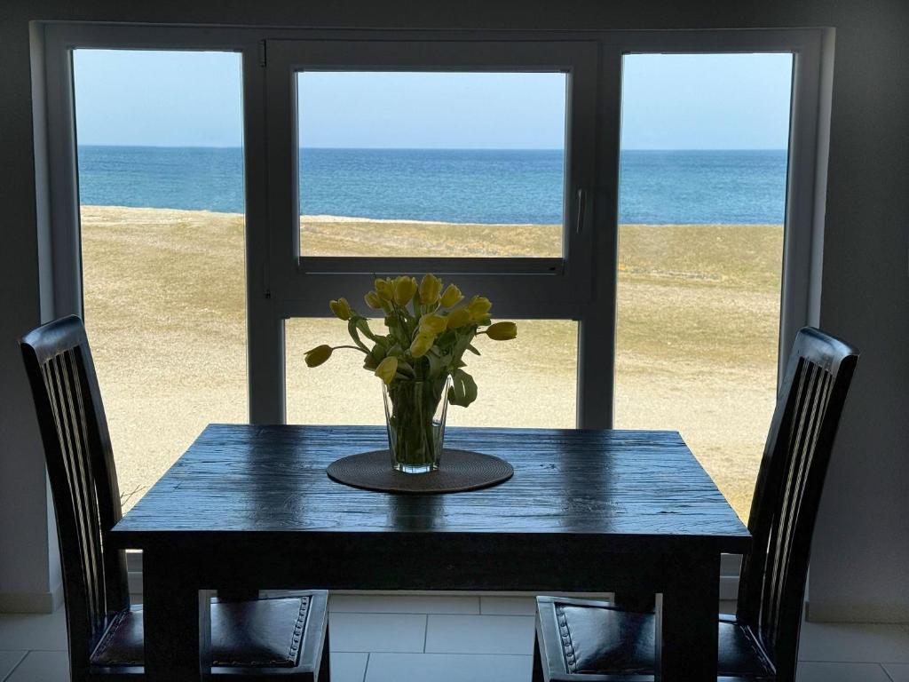 a table with a vase of flowers on top of the beach at Apartment Potosi Teichhof Fehmarn in Wenkendorf