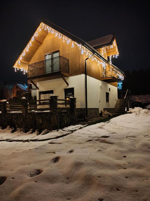 a house with lights on it in the snow at Pienińskie Zacisze in Jaworki