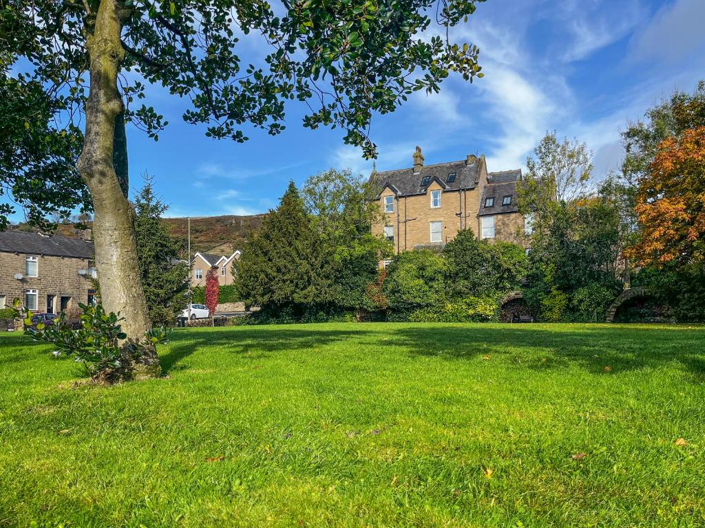 a large grassy yard in front of a large house at Studio On The Green - Uk48298 in Chinley