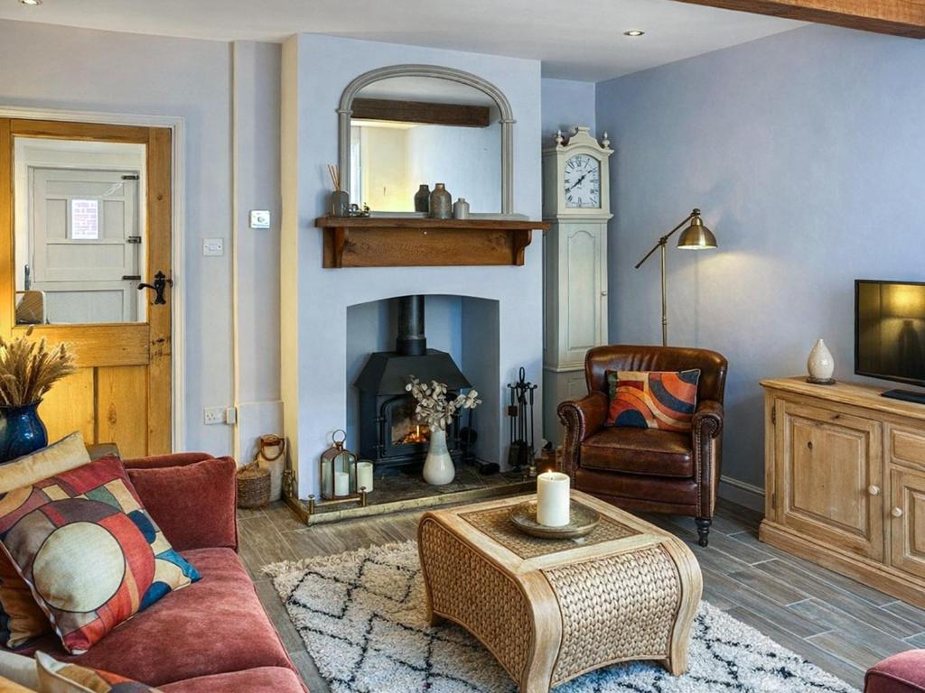 a living room with a couch and a fireplace at Time Cottage in Coltishall