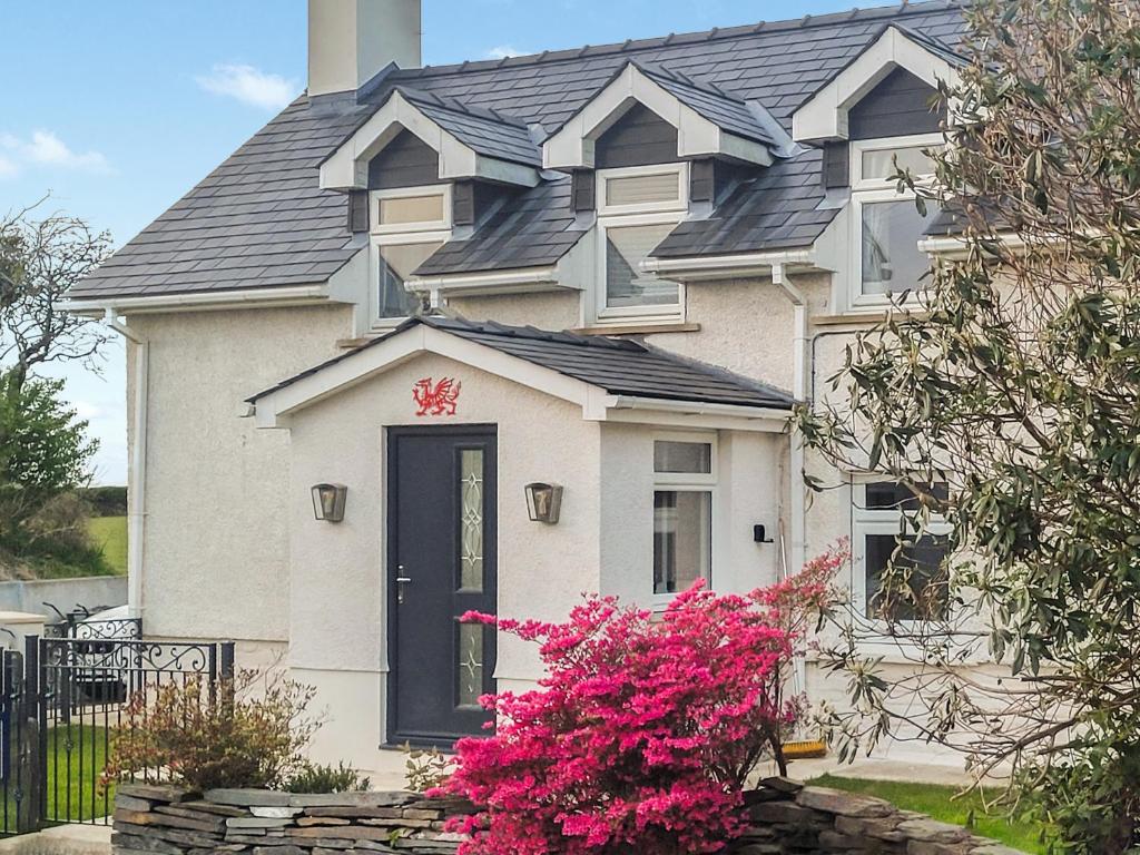 a white house with a black door and pink flowers at Rhoshill in Llanfyrnach