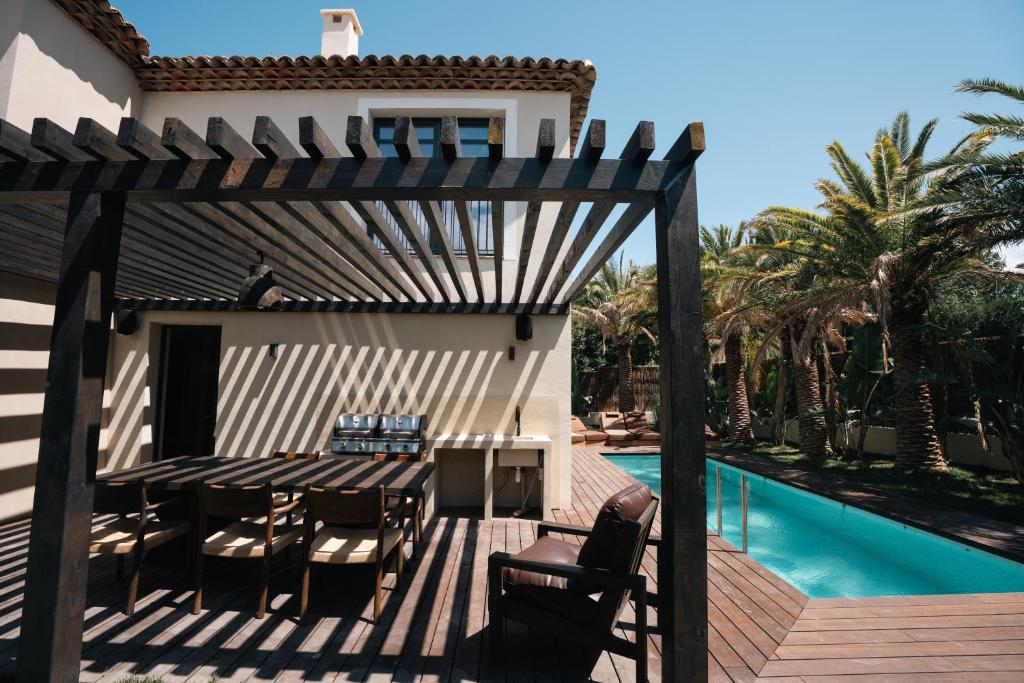 a wooden deck with a table and chairs next to a swimming pool at La Vague - Saint Tropez in Saint-Tropez