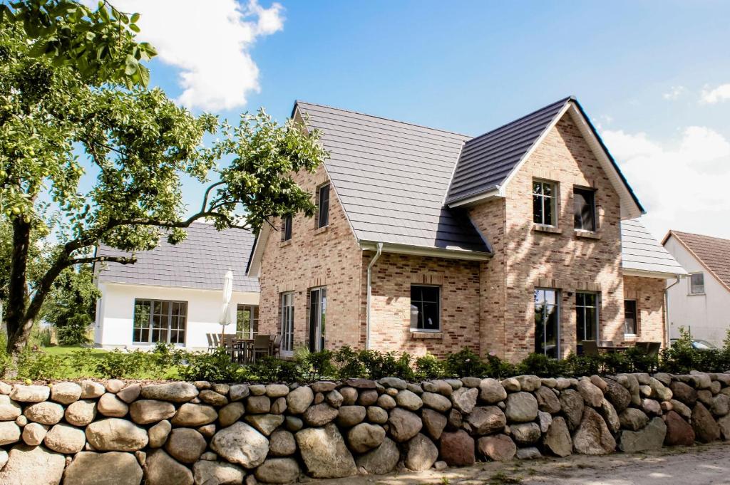 a house with a stone fence in front of it at Ferienhaus Libelle - Feriendomizil für 14 Pers - Haupt- und Nebenhaus in Rankwitz