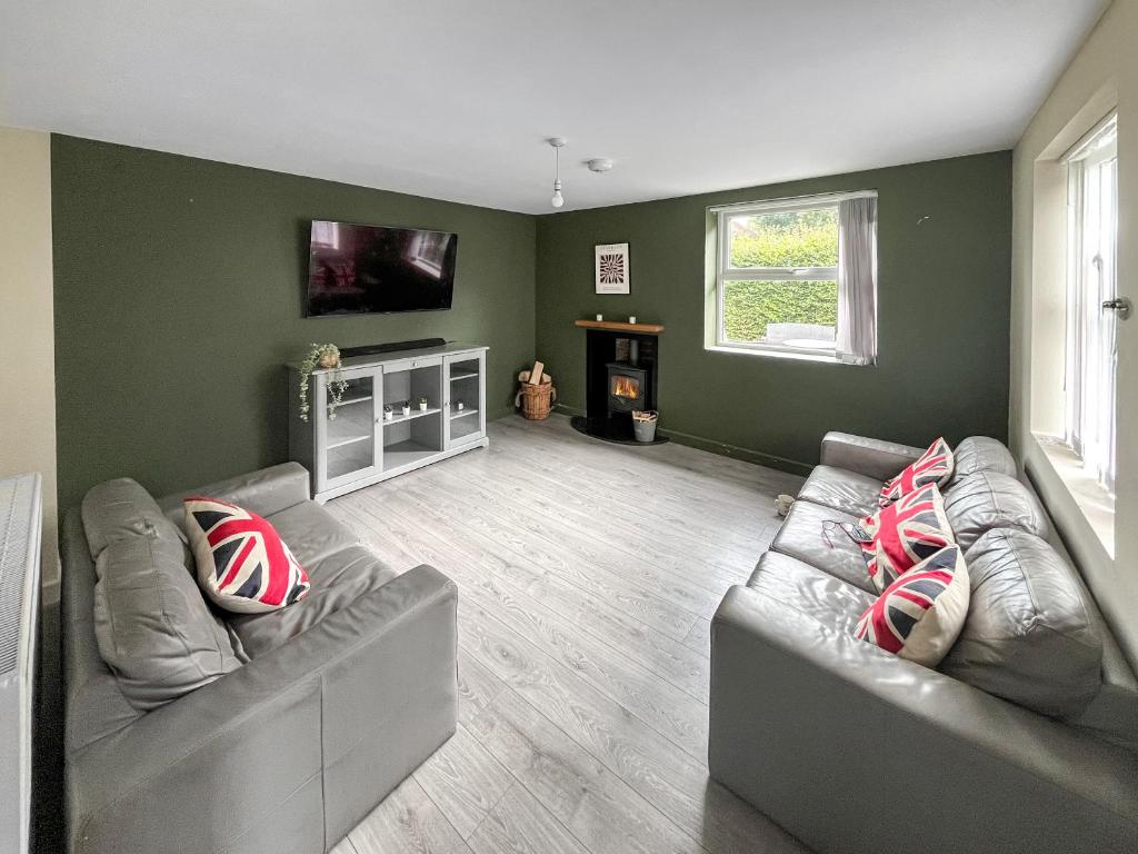 a living room with two couches and a tv at Forge Cottage in Canterbury
