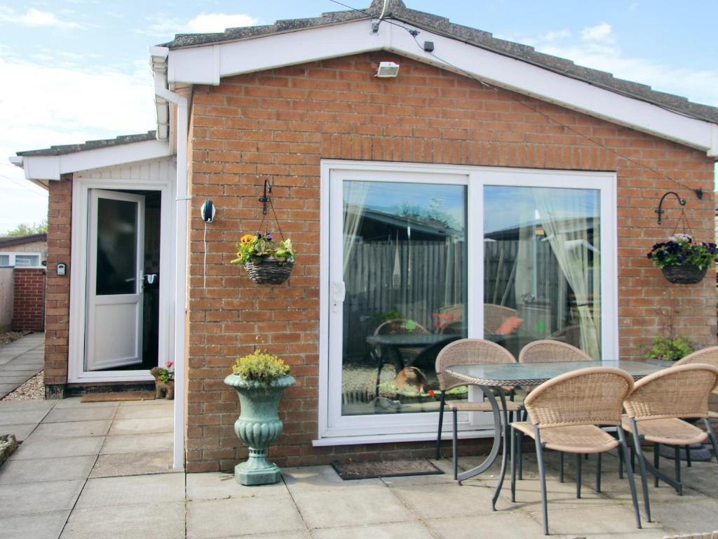 a patio with a table and chairs in front of a house at Sandy Creek Cottage - E5349A in Anderby