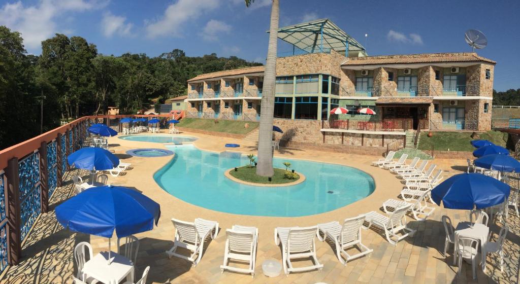 a resort with a pool with chairs and umbrellas at Camping Quedasdagua in Itu