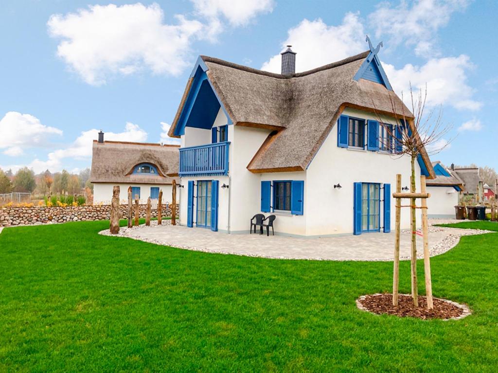 a large white house with blue windows and a roof at Kramerhof Rügenblick Nr 30 in Parow
