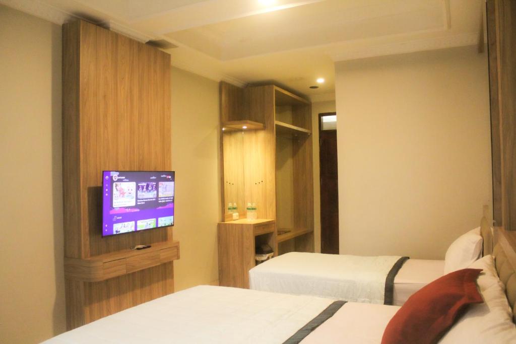 a hotel room with two beds and a flat screen tv at Hotel Indria in Bukittinggi