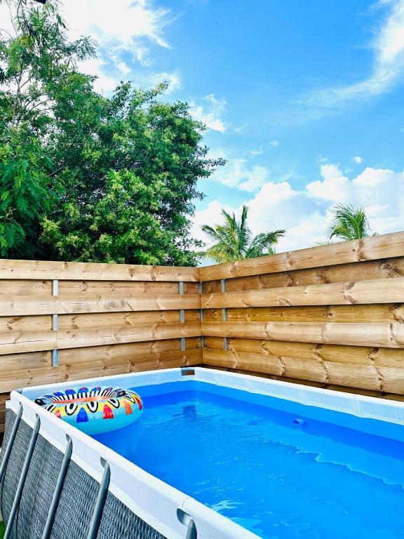 a backyard swimming pool with a wooden privacy fence at La Kaz Eden * * * * in Les Cocos