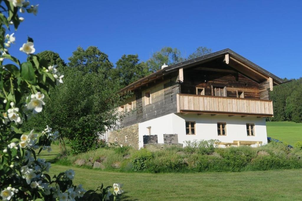 a house with a wooden roof on a green field at Chalet Schmuckkastal in Kollnburg