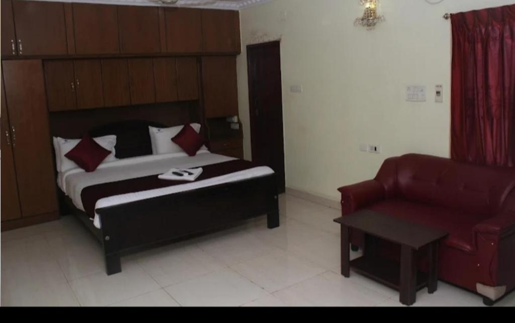 a bedroom with a bed and a chair and a couch at Hotel Raaj Inn Service Apartment in Chennai