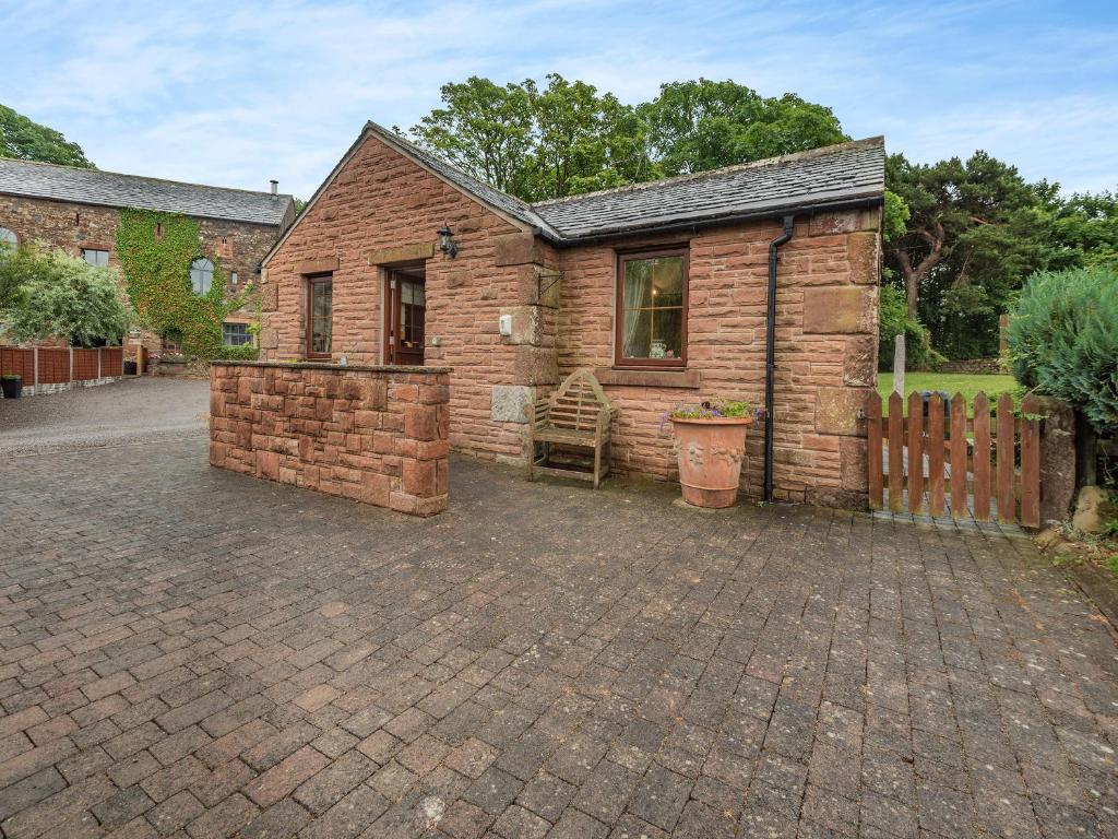 a small brick house with a fence and a patio at Beckside in Gilcrux