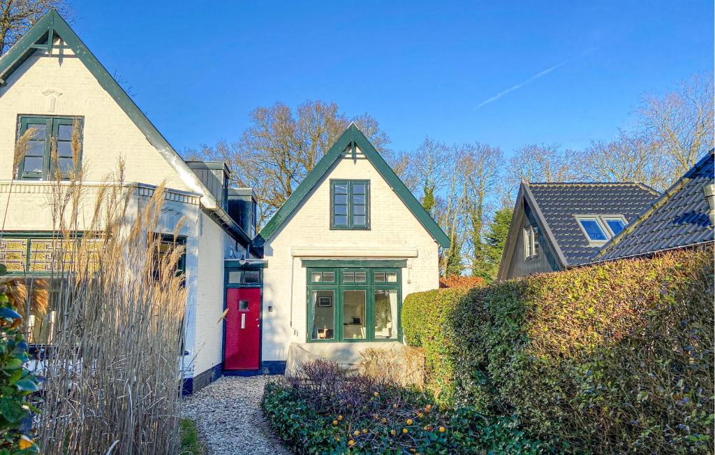 a white house with a red door in a yard at Klein Maar Fijn in Bergen