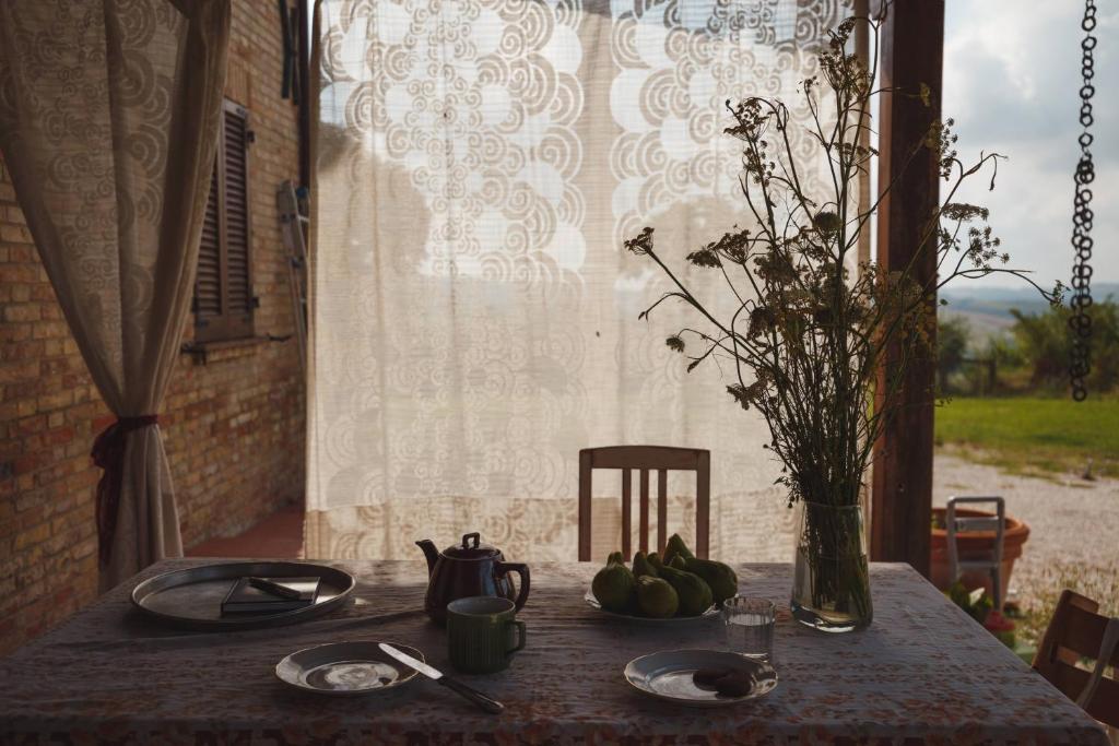 a table with plates and a vase with fruit on it at B&B Le Tamerici in San Giorgio di Pesaro