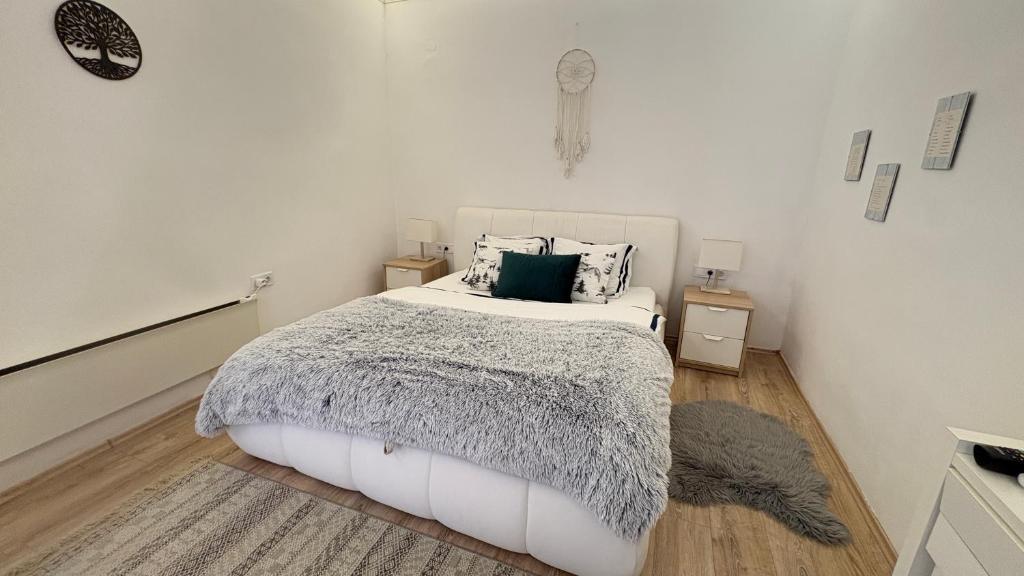 a bedroom with a white bed with a gray blanket at Manland Vendégház Lillafüred in Lillafüred