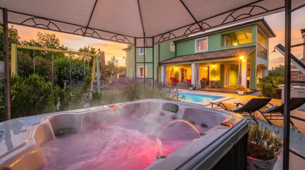 a bath tub filled with water in front of a house at Spacious holiday house / pool / jacuzzi / playground / 6+2 in Rakalj