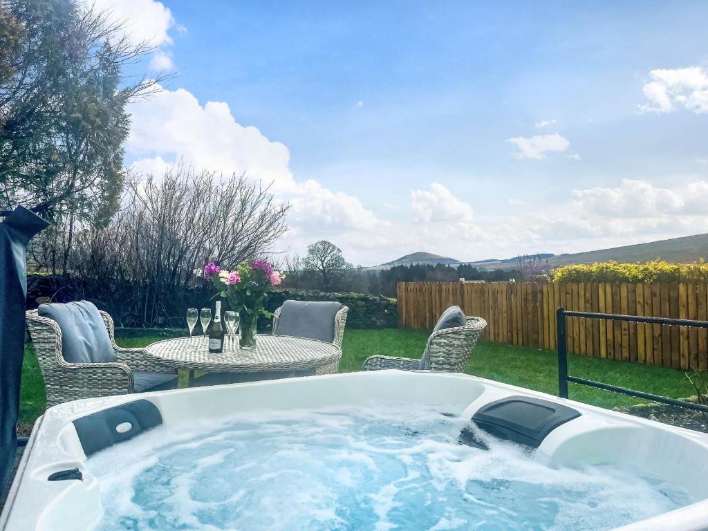a hot tub in a yard with a table and chairs at Garth Cottage in Keswick